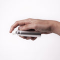 Hand holding the Überlube Good-to-Go silver travel lubricant case