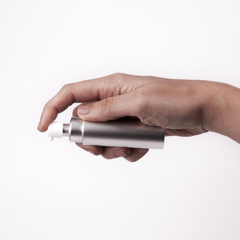 Hand holding the Überlube Good-to-Go silver travel lubricant case