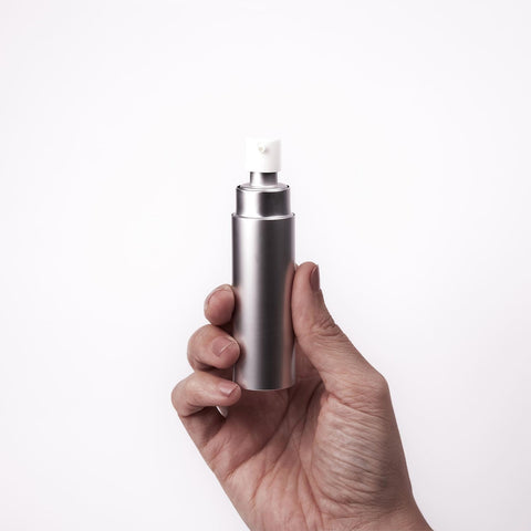 Hand holding the Überlube Good-to-Go silver travel lubricant