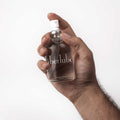Hand holding a 112 ml Überlube silicone lubricant glass bottle