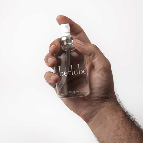 Hand holding a 112 ml Überlube silicone lubricant glass bottle