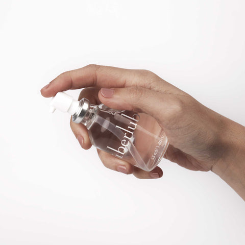 Hand pressing the pump on a 55 ml Überlube silicone lubricant bottle